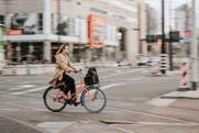 mujer con abrigo marrón montando en bicicleta negra en la carretera durante el día