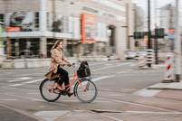 mujer con abrigo marrn montando en bicicleta negra en la carretera durante el da