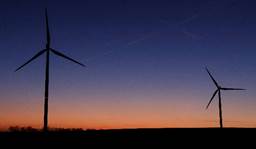 Sun sets behind power-generating windmill turbines near Waremme